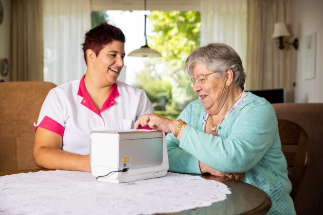 Fundamenten - zorgprofessional en oudere vrouw zitten samen aan tafel